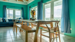 A bright room with teal walls, a wooden dining table, and a sofa.