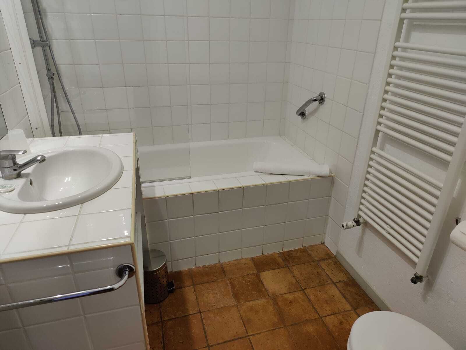 A bathroom with a white sink, a bathtub, and a toilet.