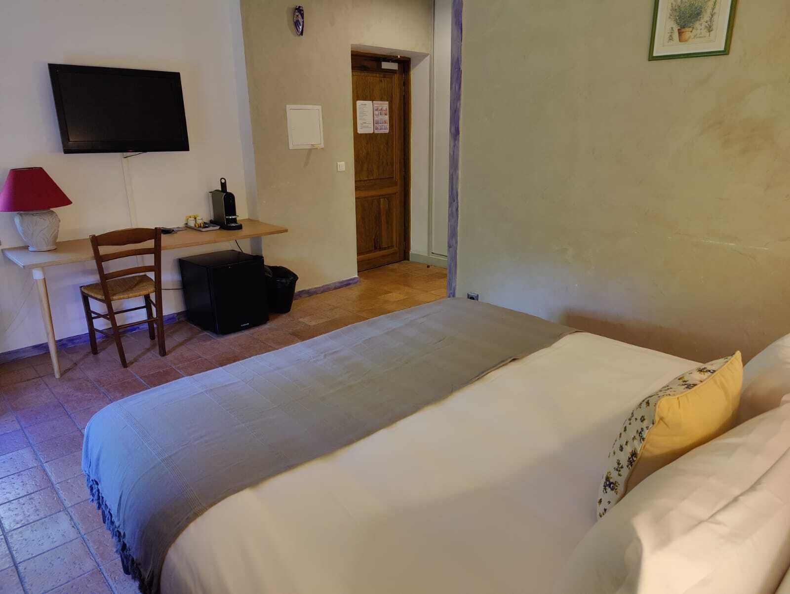 Un dormitorio con cama, escritorio, silla, televisor y puerta.