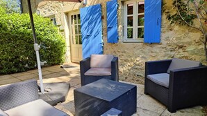 Un espacio exterior con mobiliario de mimbre y una pérgola.