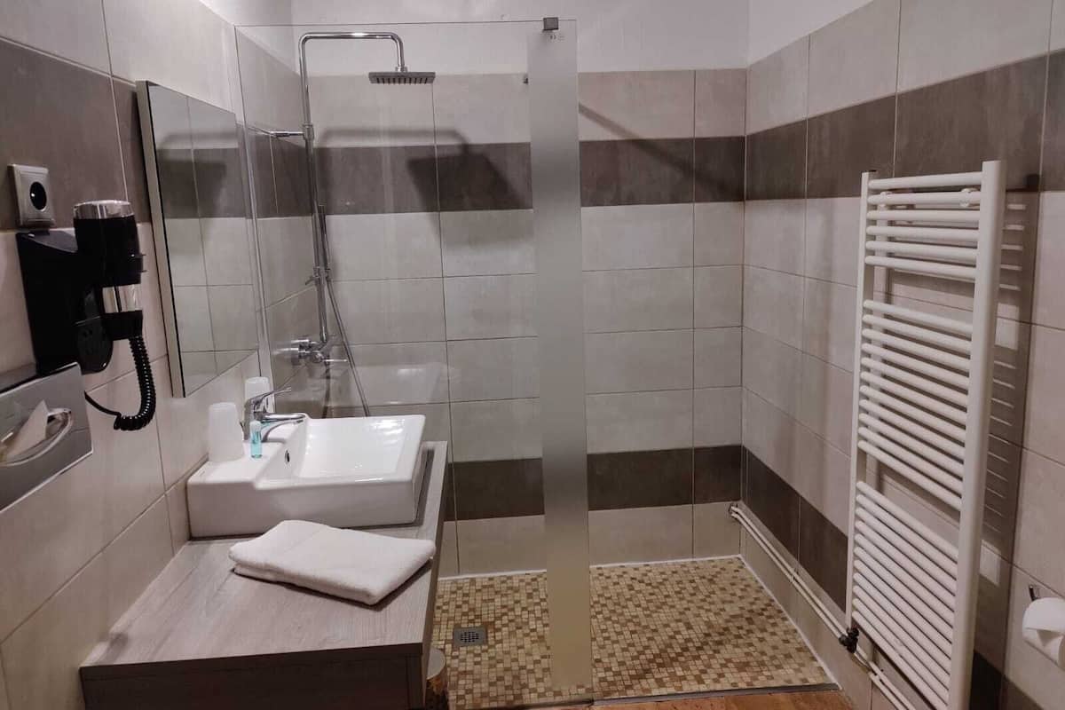 Uma casa de banho moderna com cabine de duche em vidro, lavatório, toalha e sanita.