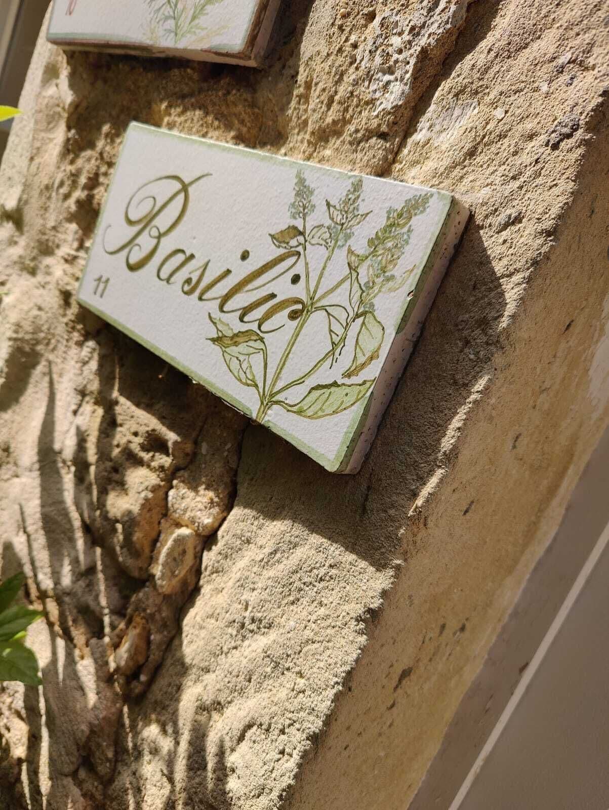 Een huisnummerbord met de naam 'Basilica' op een gestructureerde muur.