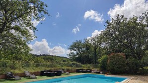 Una piscina rectangular rodeada de césped y una valla de metal.