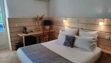 Een slaapkamer met een bed, nachtkastje, lamp en een klein bureau met stoel.