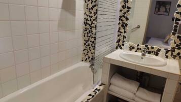 A bathroom with a white bathtub, a sink with a mosaic backsplash, and a mirror above the sink.