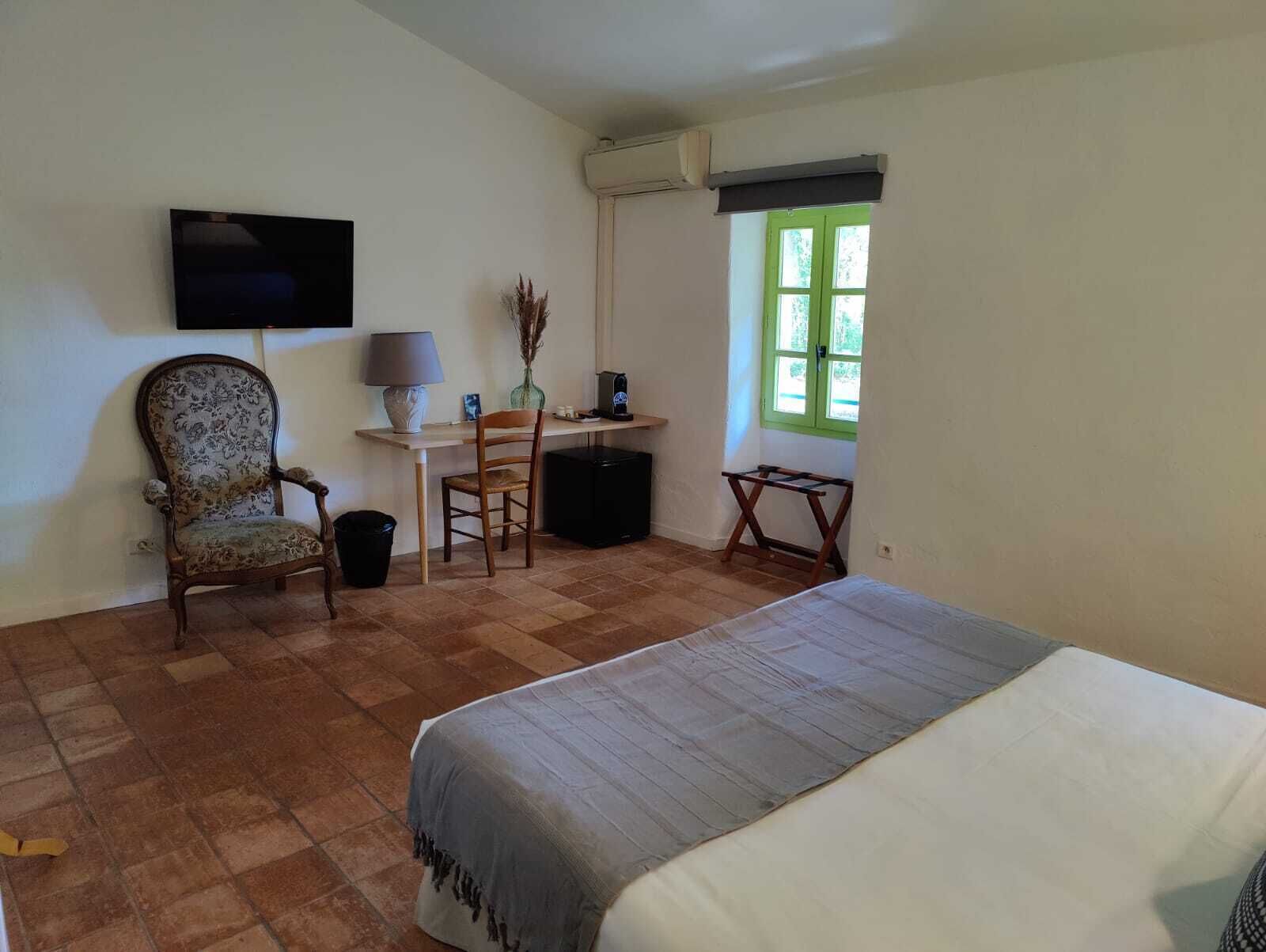 Un dormitorio con cama, escritorio, silla, televisor y ventana.