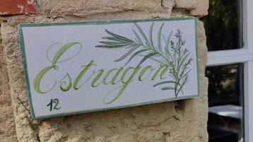 A sign with the name "Estragon" and the number 12, attached to a textured wall with a blue plastic object nearby.