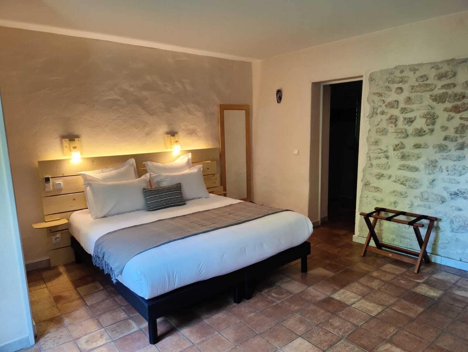 A bedroom with a bed, bedside tables, a nightstand, a wooden chair, and a door leading to another room.
