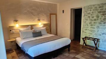 A bedroom with a bed, bedside tables, a nightstand, a wooden chair, and a door leading to another room.