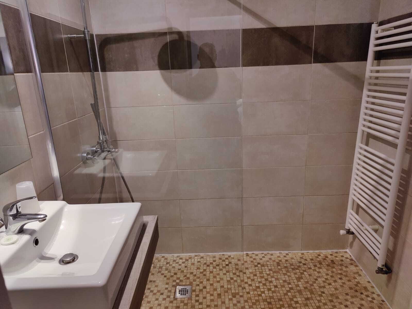 Ein Badezimmer mit Dusche, Waschbecken und Fliesenboden.