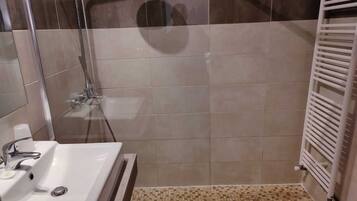Un baño con ducha, lavabo y piso de baldosas.