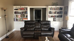 A living room with a leather sofa, wooden coffee table, and bookshelves filled with books.