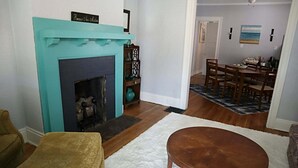 Ein Wohnzimmer mit Kamin, eine Essecke mit Tisch und Stühlen sowie ein Flur, der zu einem weiteren Raum führt.