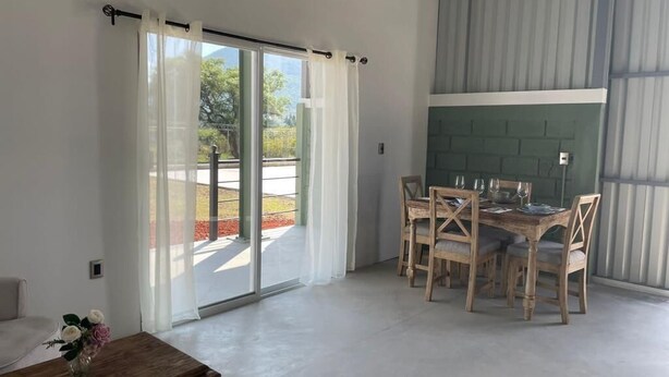 A dining area with a table and chairs, a sliding glass door leading to an outdoor space, and a view of the outdoors. - Cabaña tipo granero Granglam Ixkapada  (Ixtapan de la Sal)