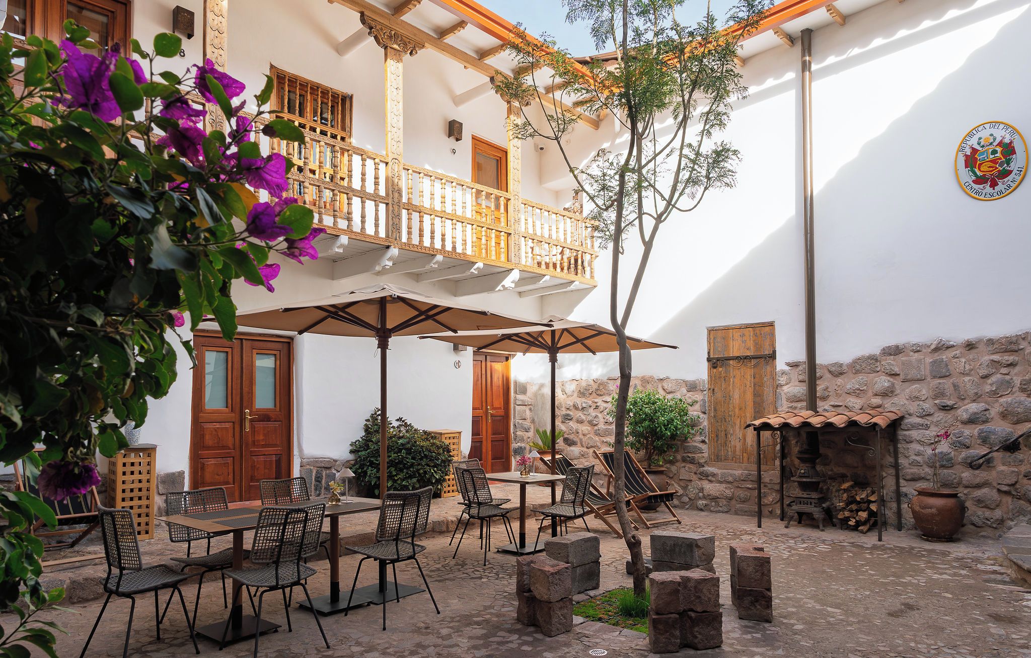 An outdoor patio with a table and chairs, a wooden door, and a stone wall.