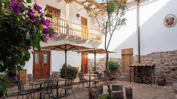 An outdoor patio with a table and chairs, a wooden door, and a stone wall.