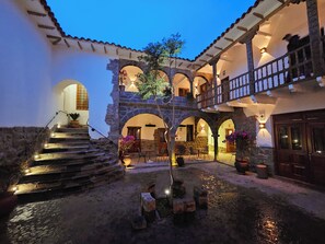 A courtyard with stone steps leading to a wooden door, surrounded by arches and potted plants. - Casa Clara by Ananay Hotels (Cusco)