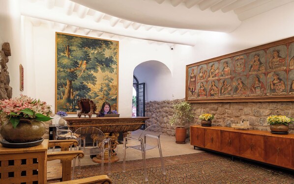 A room with a large painting, a wooden cabinet, and a stone wall. - Casa Clara by Ananay Hotels (Cusco)