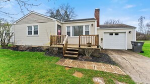 A single-story house with a garage, a front porch with steps, and a small driveway.