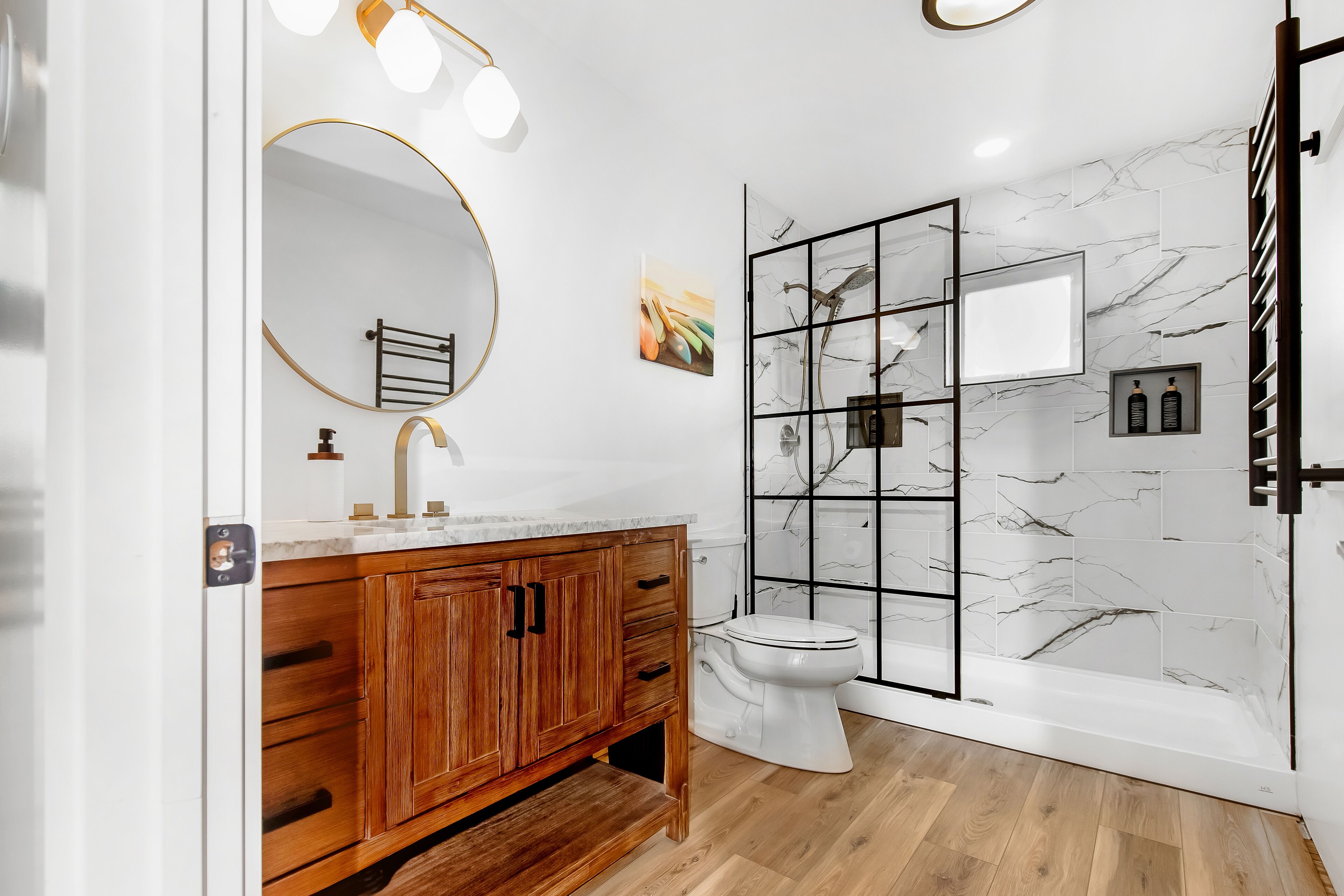 A modern bathroom with a wooden vanity, a white toilet, and a glass-enclosed shower.