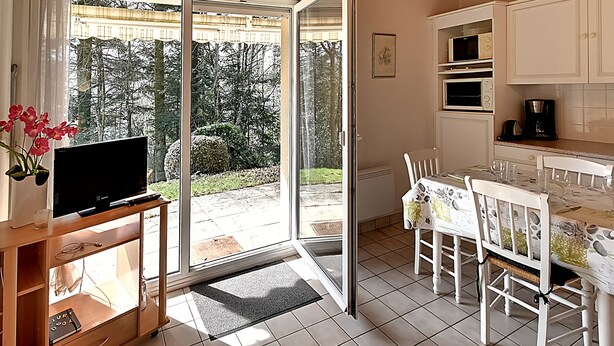 A modern kitchen with white cabinets, a dining table set for four, and a sliding glass door leading to a patio.