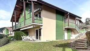 A two-story house with a balcony, a front door, and a staircase leading to the upper floor.