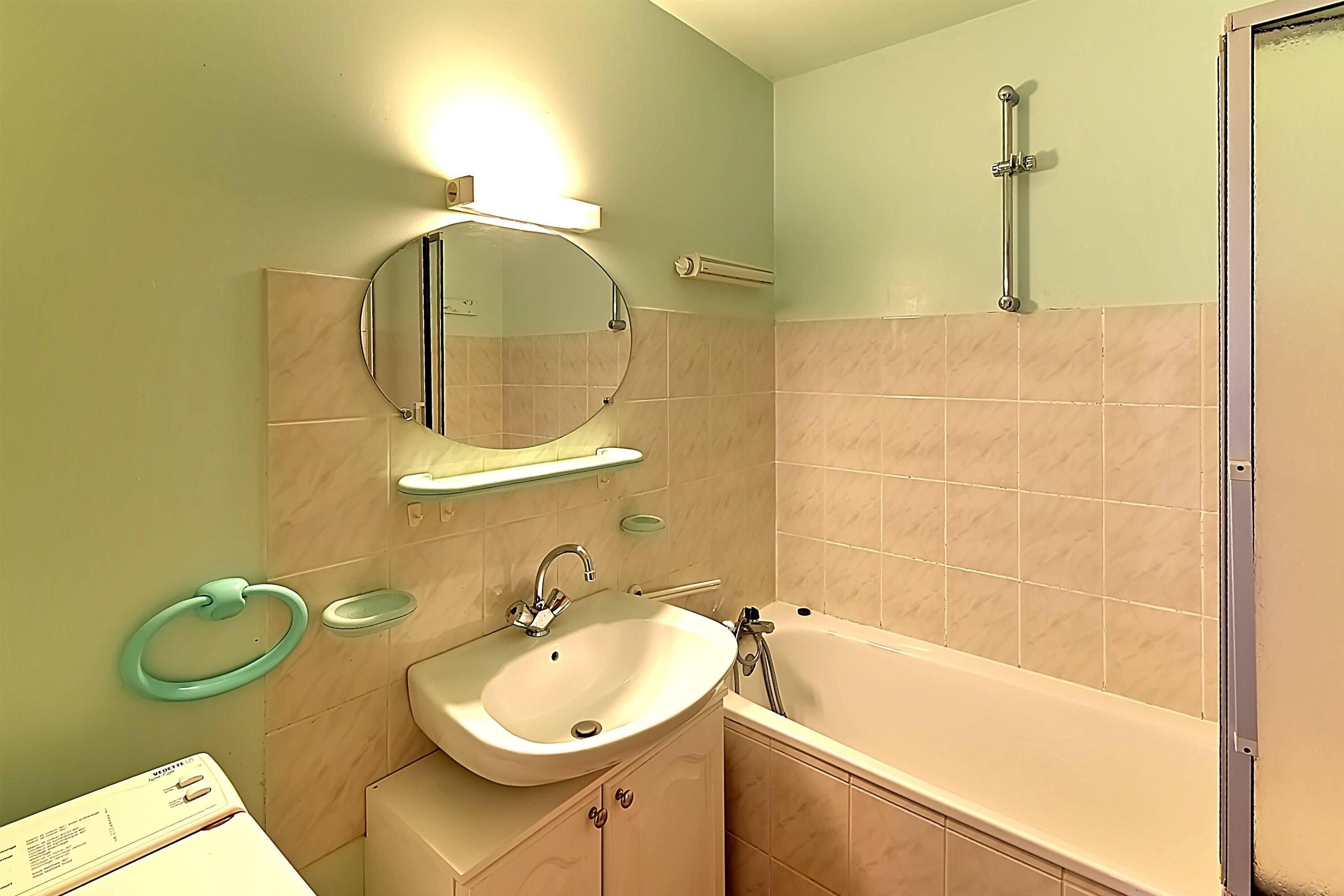 A bathroom with a sink, mirror, and bathtub.