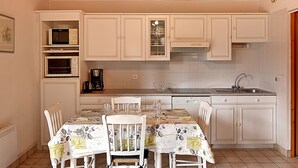 A kitchen with white cabinets, a dining table with chairs, and a microwave.