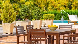 Un espace extérieur avec une piscine, une table et des chaises, le tout agrémenté de plantes en pot et d’arbres.