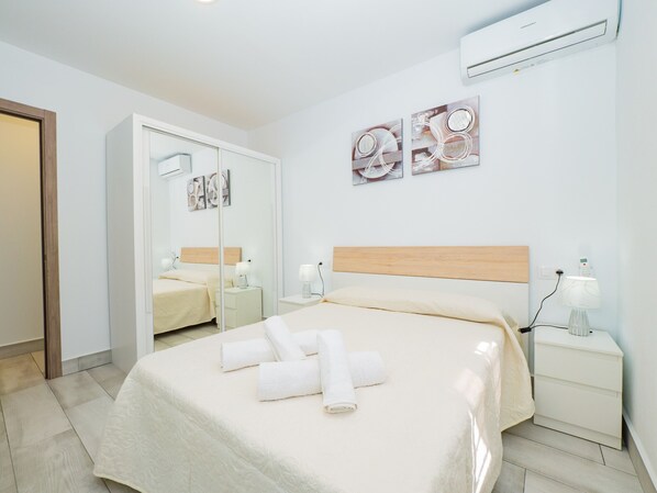 Une chambre d’hôtel avec un lit, des tables de chevet, un miroir et des œuvres d’art accrochées au mur.
