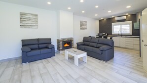 Un salon moderne avec deux canapés gris, une table basse blanche et une cheminée.