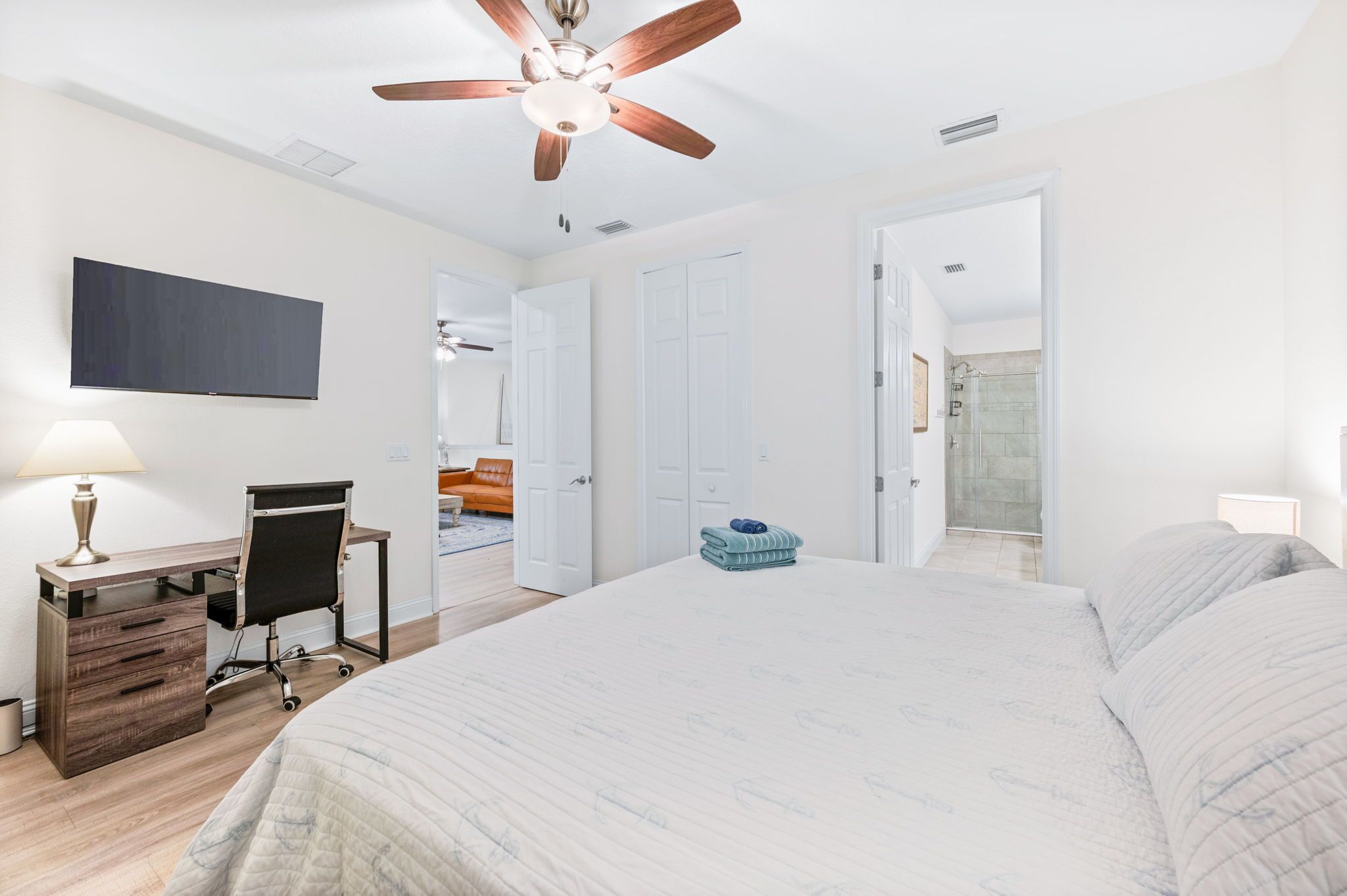 Un dormitorio con cama, escritorio, silla y ventilador de techo.