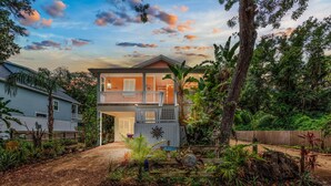 A two-story house with a balcony, surrounded by lush greenery and a wooden fence. - 🌴 Family Beach Retreat, Movie Theater, Game Room, Hot Tub, Near Ocean (Palm Coast)