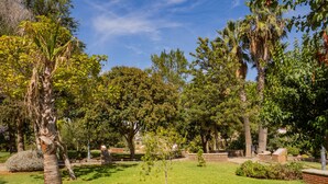 Un parc bien entretenu, avec différents types d’arbres, une pelouse verdoyante et des structures en pierre.