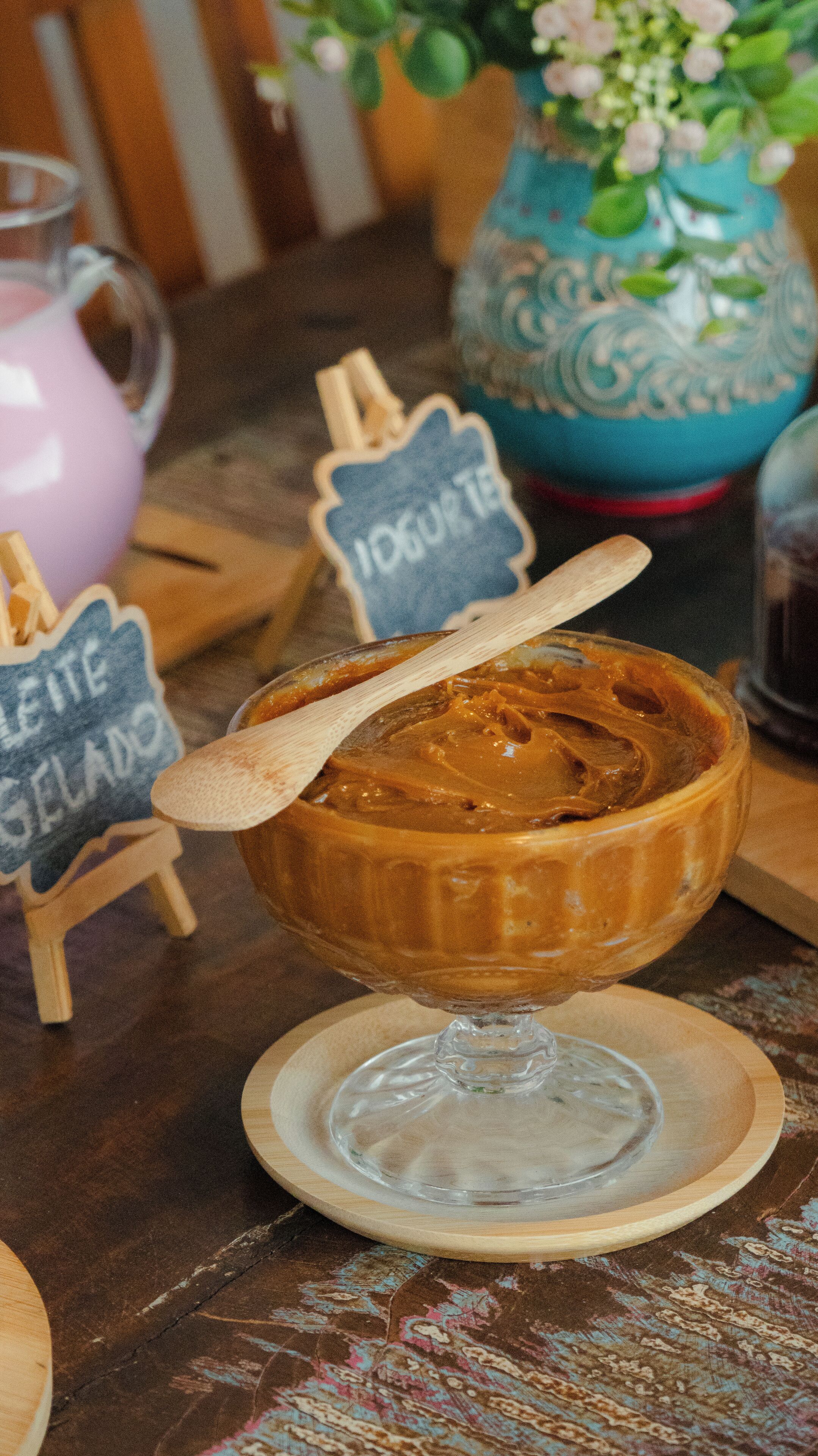 A dessert bowl of caramel pudding on a wooden table with a clear glass base.