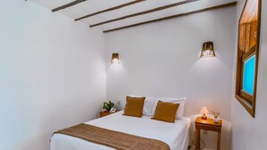 A bedroom with a bed, bedside tables, and a wall-mounted lamp. - Pousada Caraíba (Rifaina)