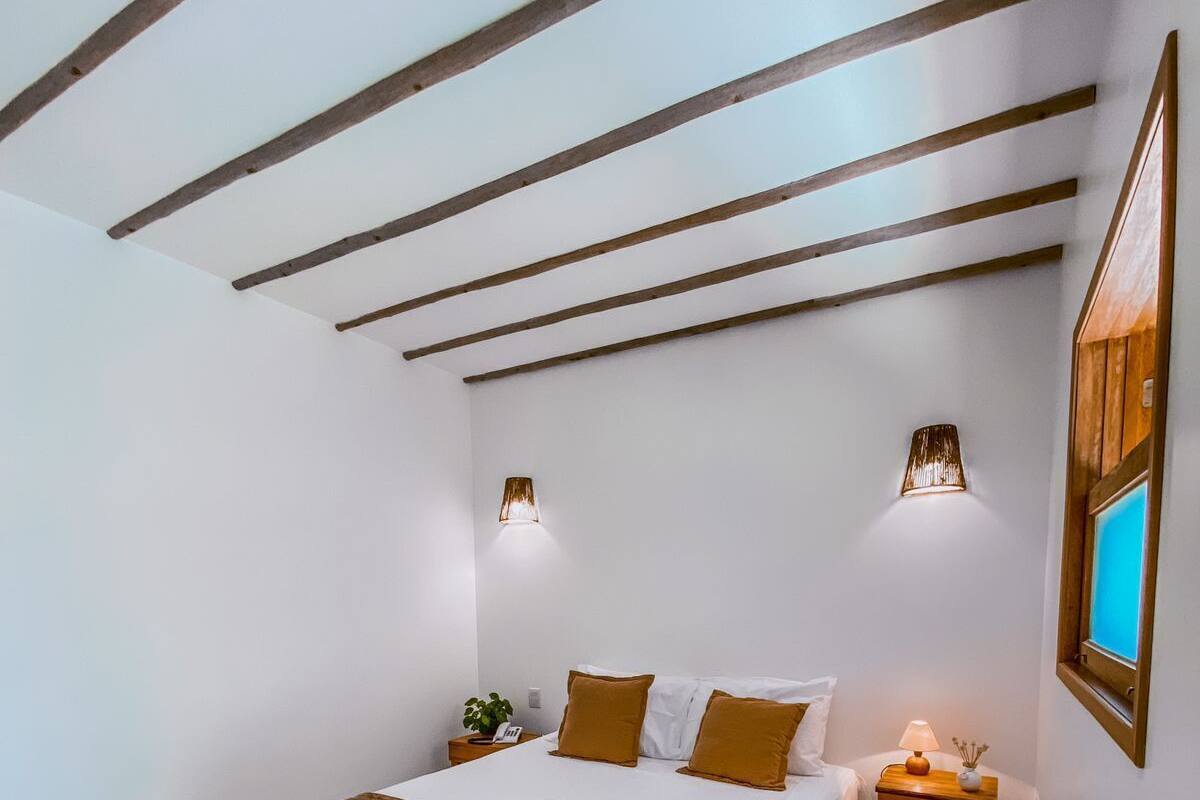 A bedroom with a bed, bedside tables, and a wall-mounted lamp.