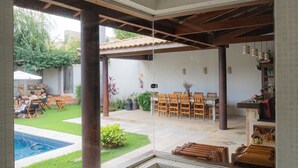 A spacious patio with a tiled floor, a pool, and a dining area with chairs and tables. - Pousada Caraíba (Rifaina)