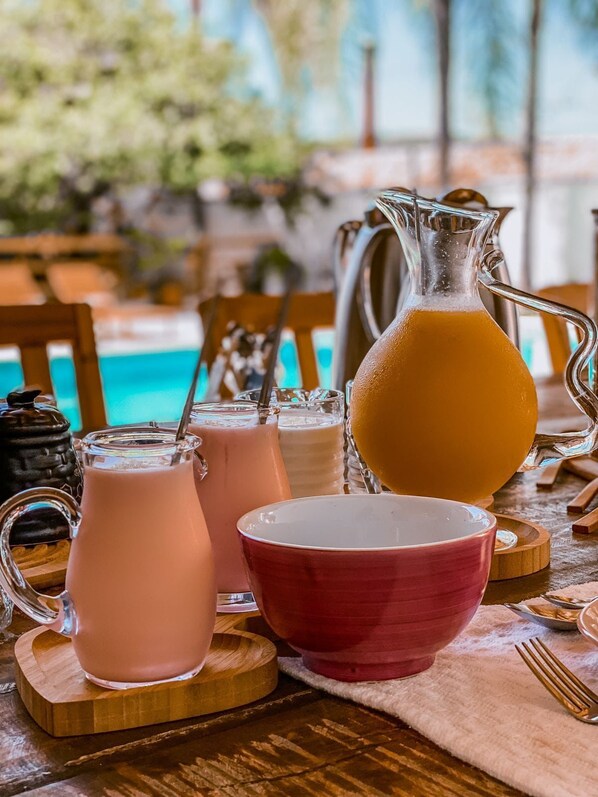 A table with drinks and a pitcher, near a pool.