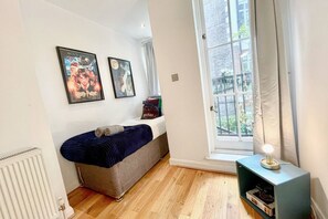 Ein Schlafzimmer mit einem Bett, einem Fenster und zwei Bildern an der Wand.