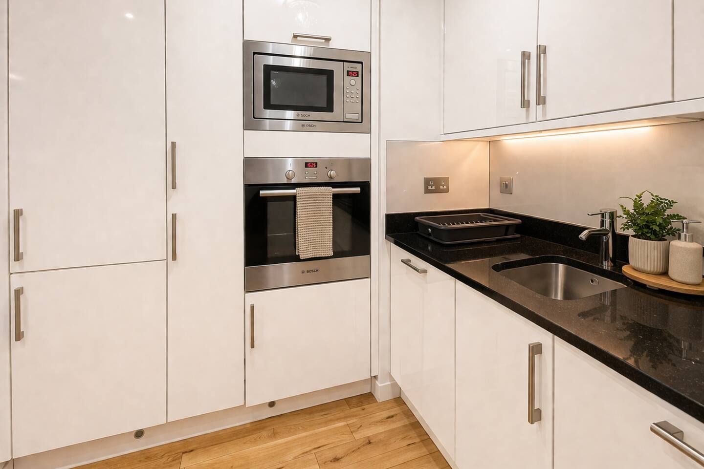 A modern kitchen with white cabinets, stainless steel appliances, and a black countertop.