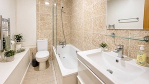 Un baño moderno con inodoro, bañera y dos lavamanos.