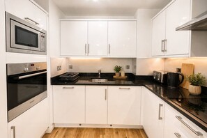 A modern kitchen with white cabinets, stainless steel appliances, and a black countertop.