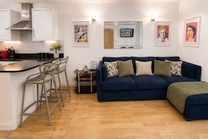 A modern living space with a kitchen, bar stools, a sofa, and artwork on the walls.