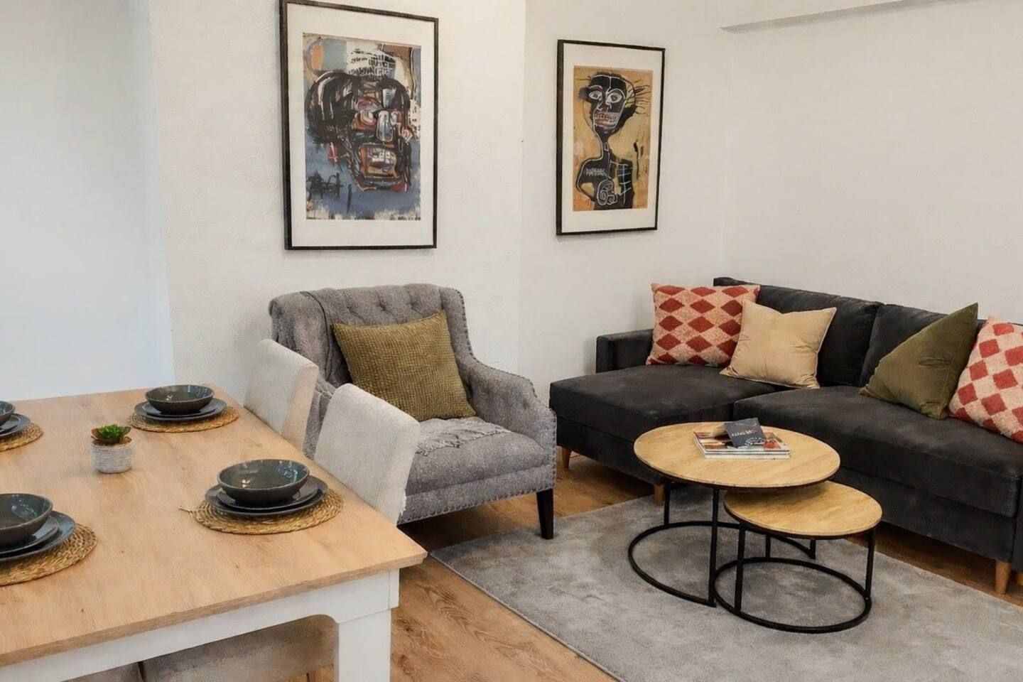 Un salon comprenant un canapé, un fauteuil, une table basse et une table à manger avec des bols.
