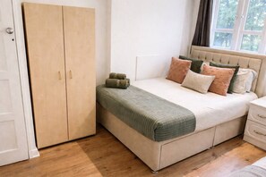 A bedroom with a bed, a wardrobe, and a window. - Bright 3 Bed flat with Balcony near Finsbury Park (Harringay)