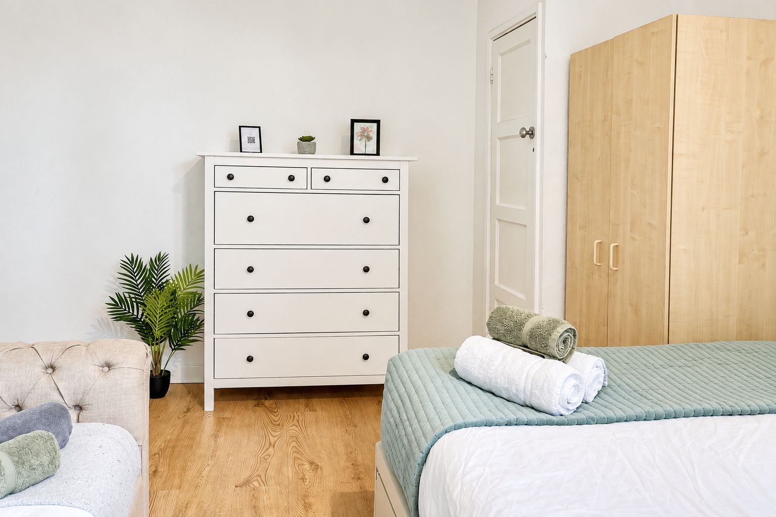 Une chambre à coucher avec un lit, une commode, une armoire et une plante en pot.