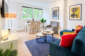 A modern living room with a dining area, a large window, and artwork on the walls. - Bright 3 Bed flat with Balcony near Finsbury Park (Harringay)