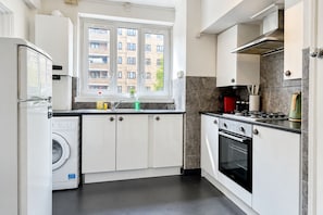Eine moderne Küche mit Einbauwaschmaschine, Herd und Fenster mit Blick auf eine Wohngegend.