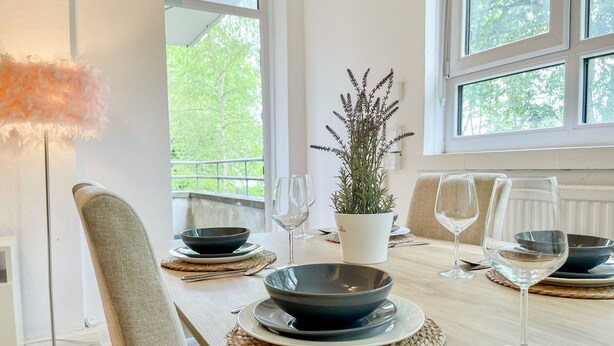 Et spisebord dækket med skåle, vinglas og en potteplante.